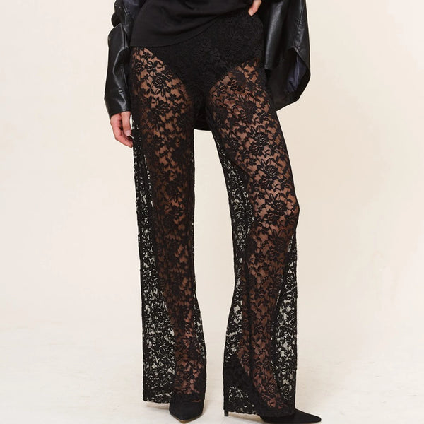 Front view of a model wearing black sheer floral lace trousers with flared legs