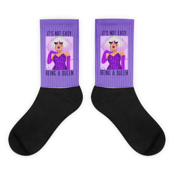Pair of black-and-purple socks showing a glamorous illustrated queen and “IT’S NOT EASY BEING A QUEEN”