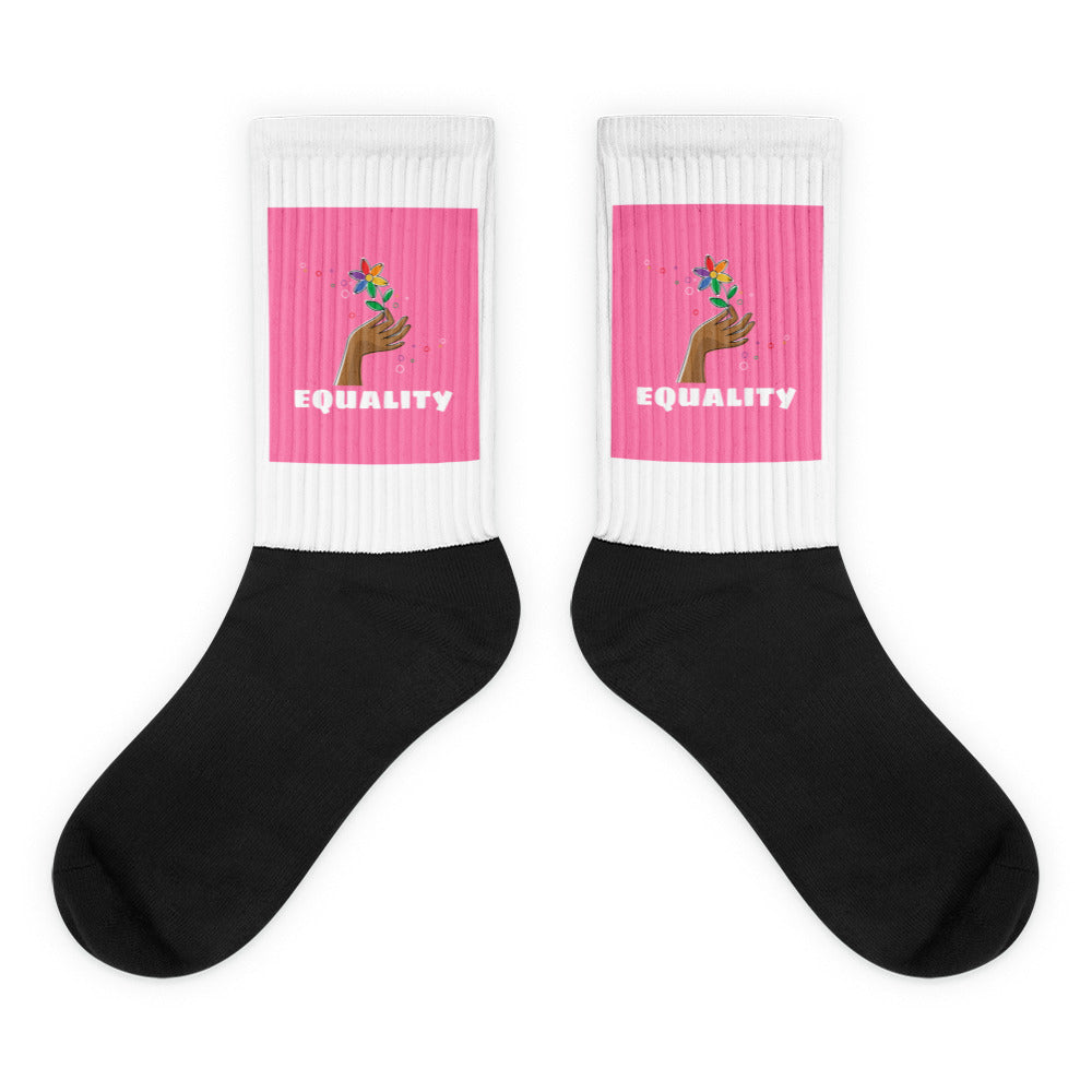 Pair of black socks with white ribbed cuffs, pink panels, and “EQUALITY” text