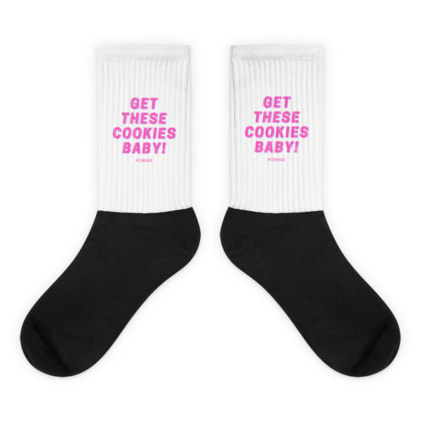Pair of white-and-black crew socks reading “GET THESE COOKIES BABY!” in pink
