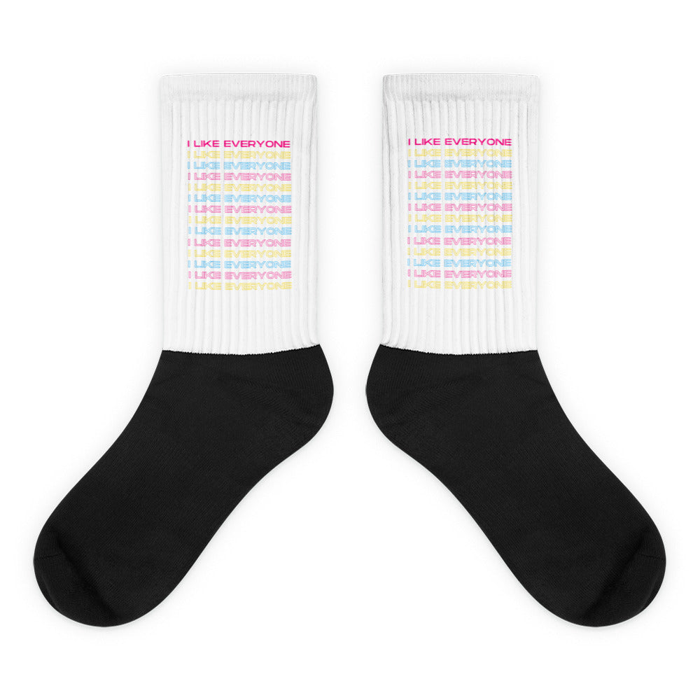 Pair of crew socks with black feet, white ribbed cuffs, and repeated pastel “I LIKE EVERYONE” text