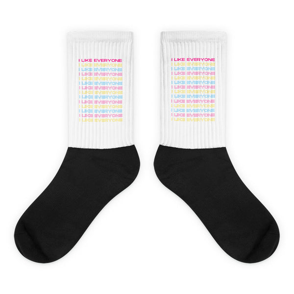 Pair of crew socks with black feet, white ribbed cuffs, and repeated pastel “I LIKE EVERYONE” text