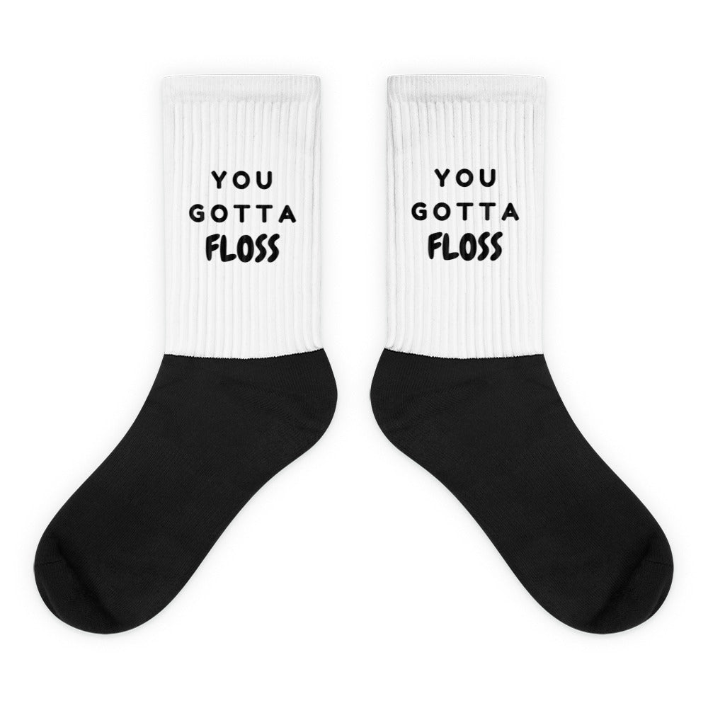 Pair of black-and-white crew socks reading “YOU GOTTA FLOSS”