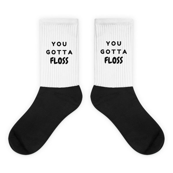 Pair of black-and-white crew socks reading “YOU GOTTA FLOSS”