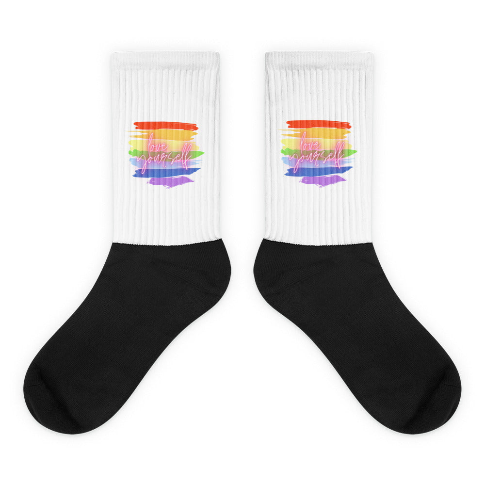 Pair of black-and-white ribbed socks with rainbow stripes and “love yourself” text
