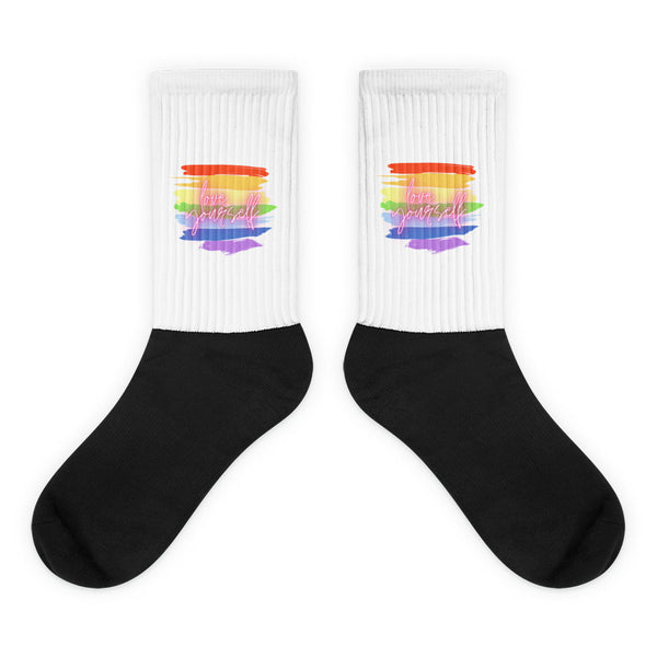 Pair of black-and-white ribbed socks with rainbow stripes and “love yourself” text