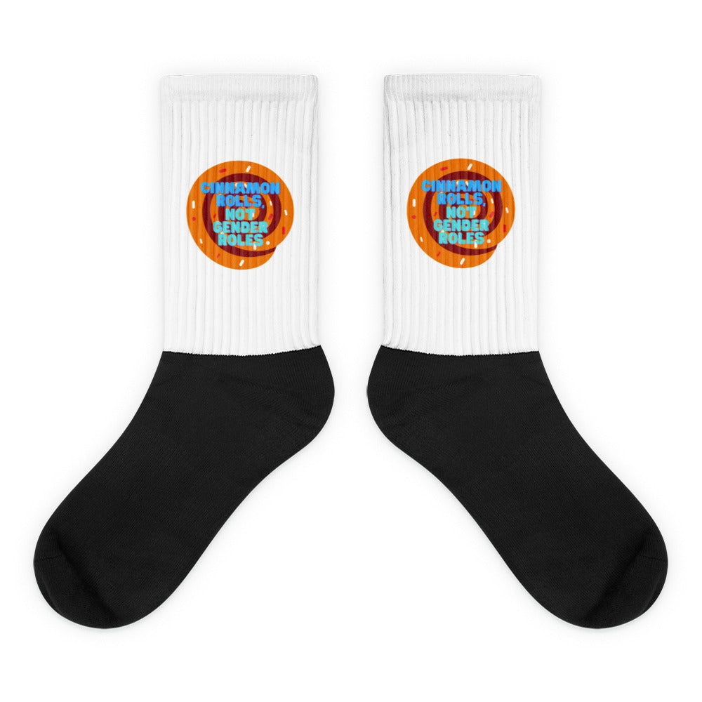 Pair of black-and-white socks with cinnamon-roll graphics and “CINNAMON ROLLS, NOT GENDER ROLES.”