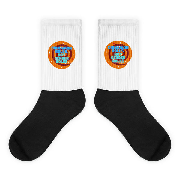 Pair of black-and-white socks with cinnamon-roll graphics and “CINNAMON ROLLS, NOT GENDER ROLES.”