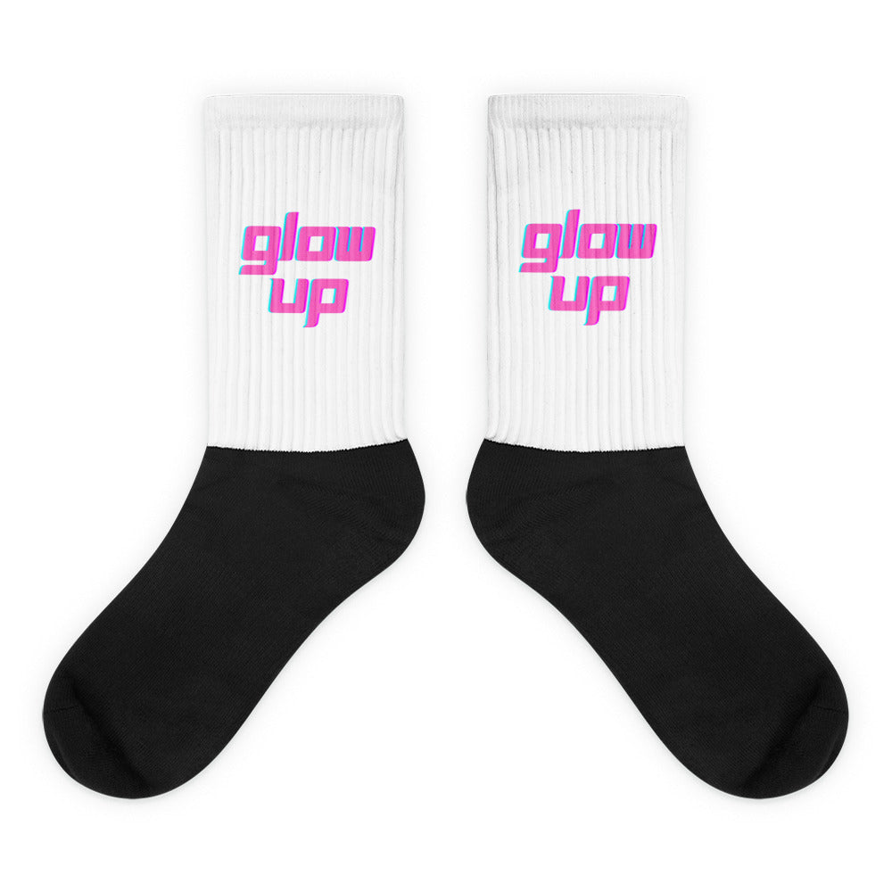 Pair of white-and-black crew socks reading “glow up” in pink and teal