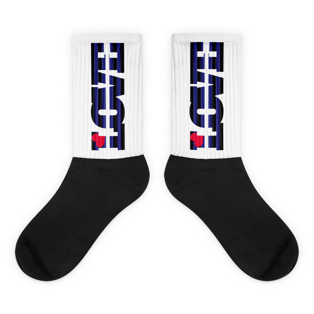 Pair of crew socks with black feet and white ribbed legs bearing black-and-blue graphics and red hearts
