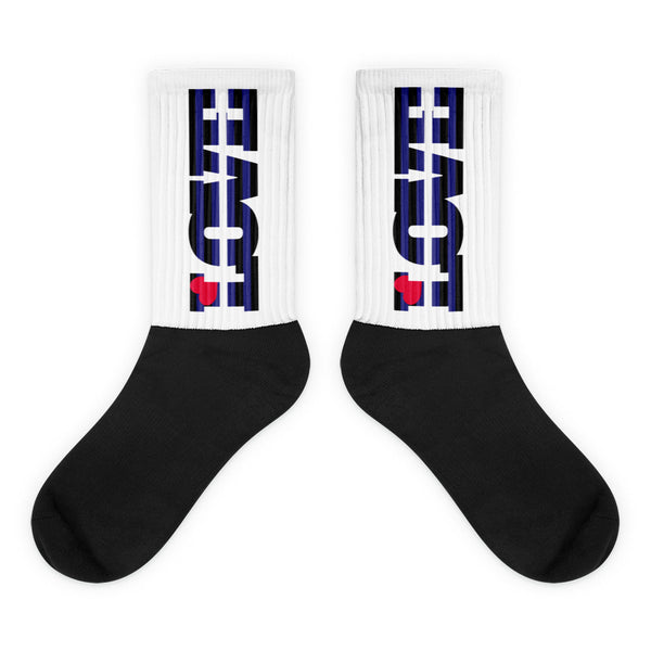 Pair of crew socks with black feet and white ribbed legs bearing black-and-blue graphics and red hearts