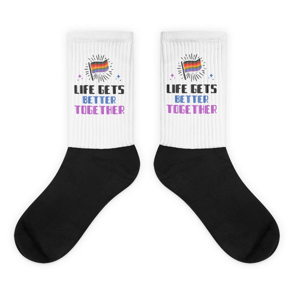 Pair of white-and-black crew socks reading “LIFE GETS BETTER TOGETHER” with rainbow flags