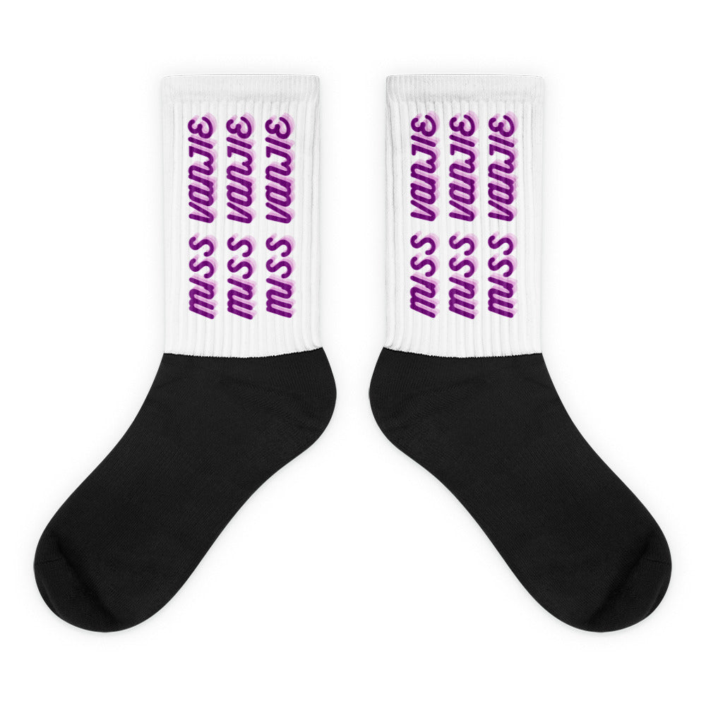 Pair of black-and-white socks with purple “Miss Vanjie” text repeated on the cuffs