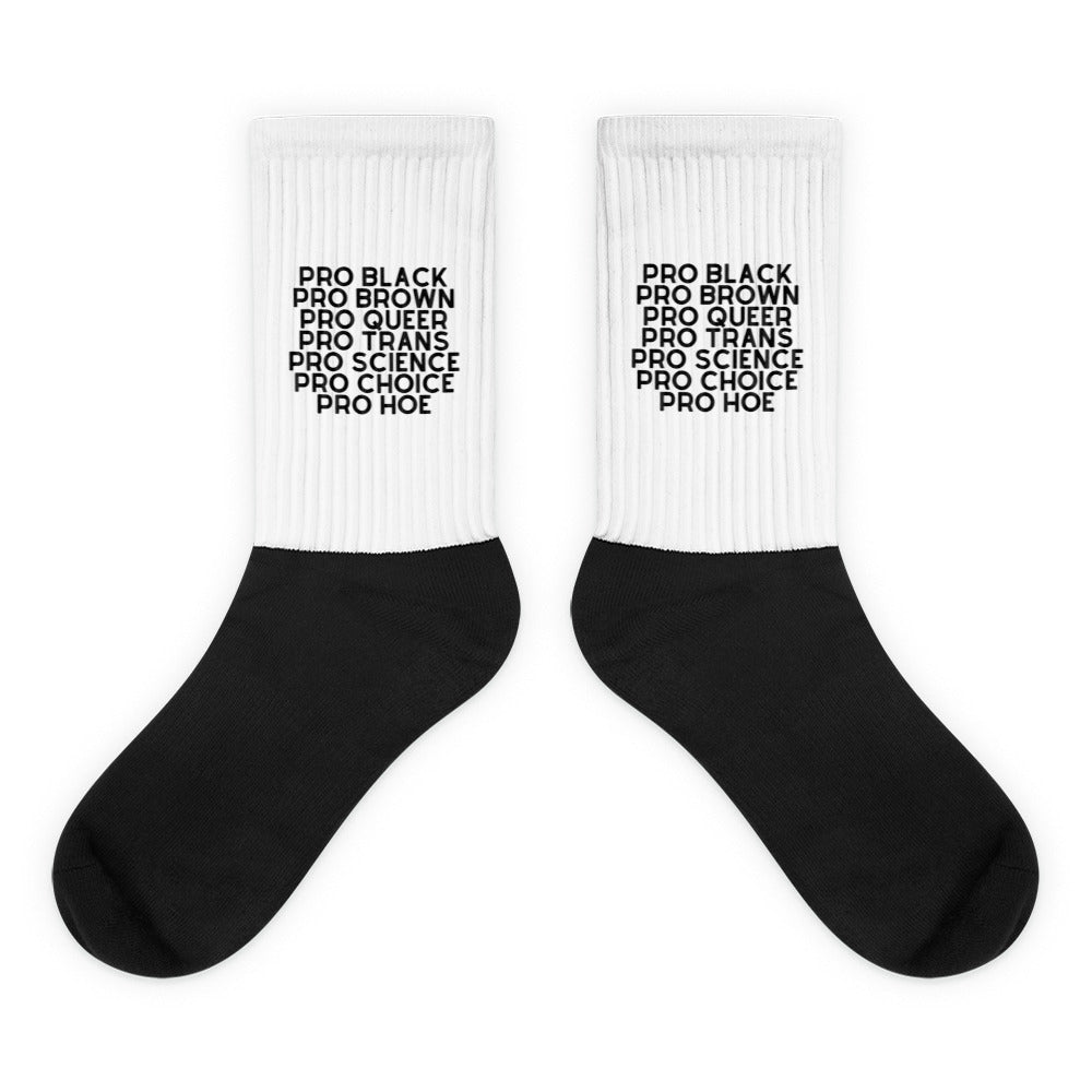 Pair of black-and-white crew socks reading “PRO BLACK PRO BROWN PRO QUEER PRO TRANS PRO SCIENCE PRO CHOICE PRO HOE”