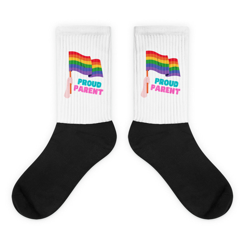Pair of white-and-black socks with rainbow flags and “PROUD PARENT” text