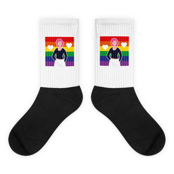 Pair of black-and-white crew socks with rainbow flags, hearts, and a cartoon figure