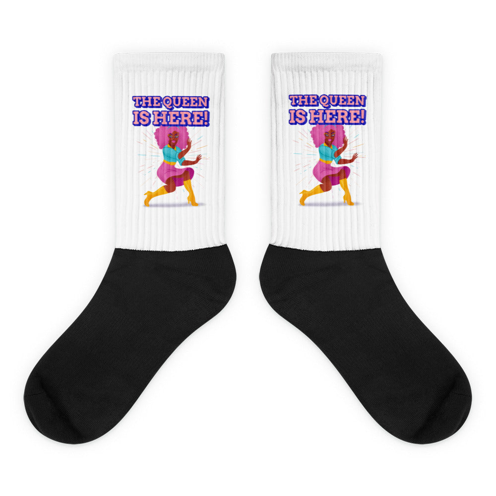 Pair of black-and-white crew socks reading “THE QUEEN IS HERE!” with a colorful dancing figure