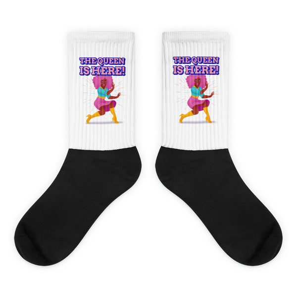 Pair of black-and-white crew socks reading “THE QUEEN IS HERE!” with a colorful dancing figure