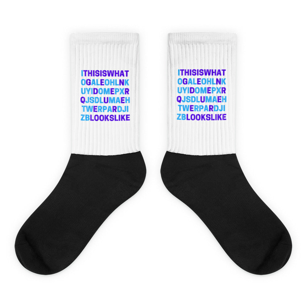 Pair of black-and-white socks with colorful text reading “This Is What Genderqueer Looks Like”