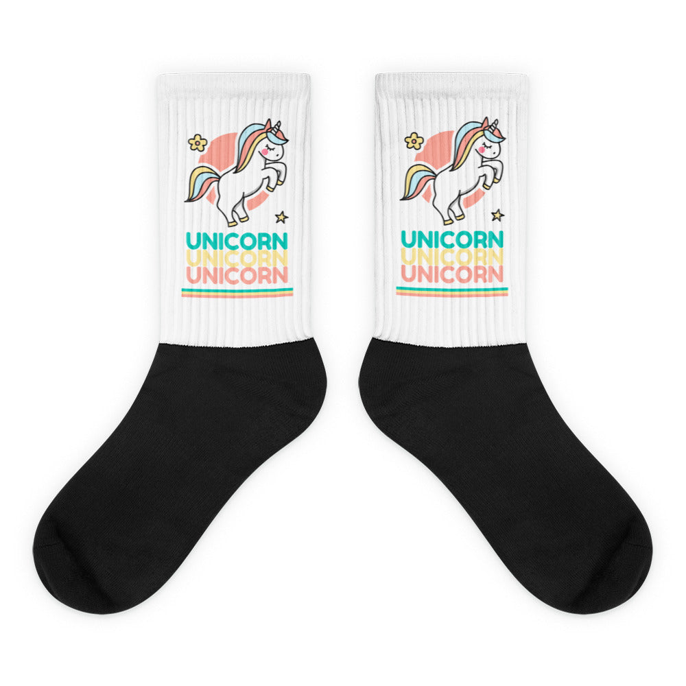 Pair of black crew socks with white unicorn-print cuffs and repeated “UNICORN” text