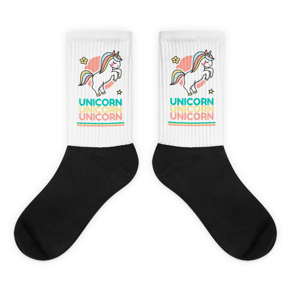Pair of black crew socks with white unicorn-print cuffs and repeated “UNICORN” text