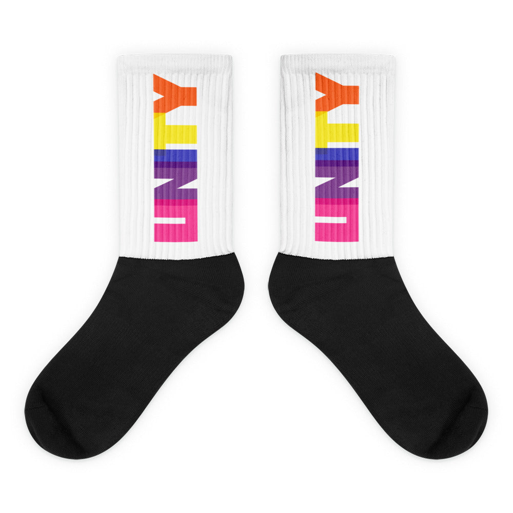 Pair of crew socks with black feet, white ribbed cuffs, and rainbow UNITY lettering