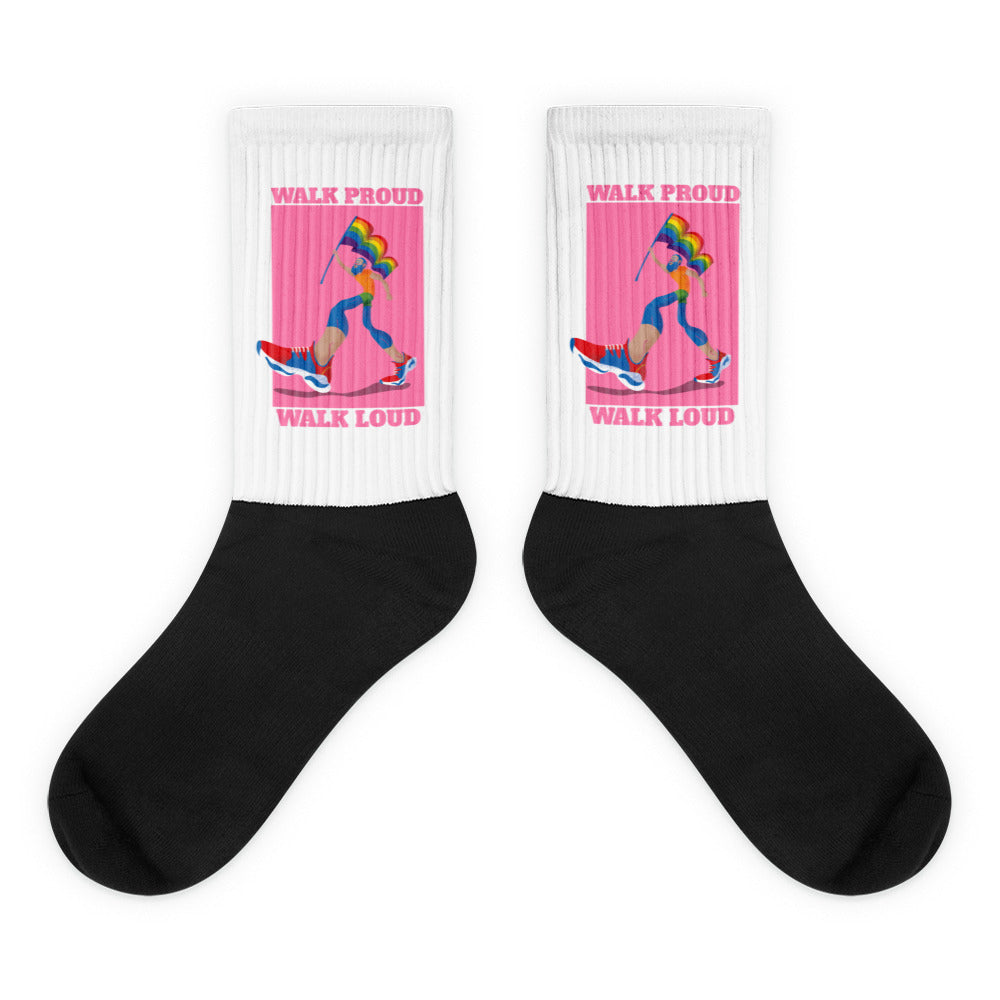 Pair of crew socks with black feet and white cuffs reading “WALK PROUD WALK LOUD”