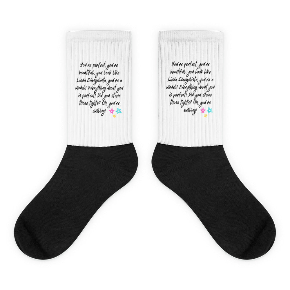 Pair of black-and-white socks with ribbed cuffs and printed praise text