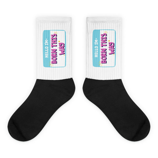 Hello I'm Born This Way Socks feature bold black feet and white legs with vibrant name-tag graphics, celebrating queer pride and self-expression with a cushioned bottom and ribbed leg for fabulous comfort.