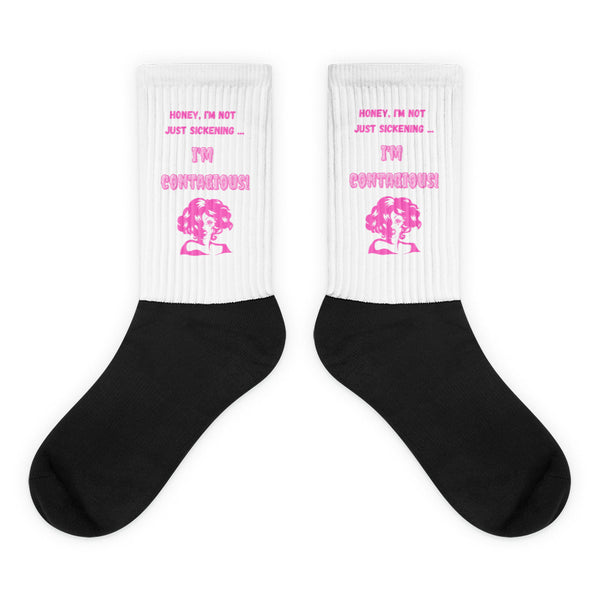 I'm Contagious Socks feature bold black feet, white cuffs with hot pink queer-themed artwork, and a sassy slogan, embodying prideful self-expression and comfort with a vibrant, inclusive design.