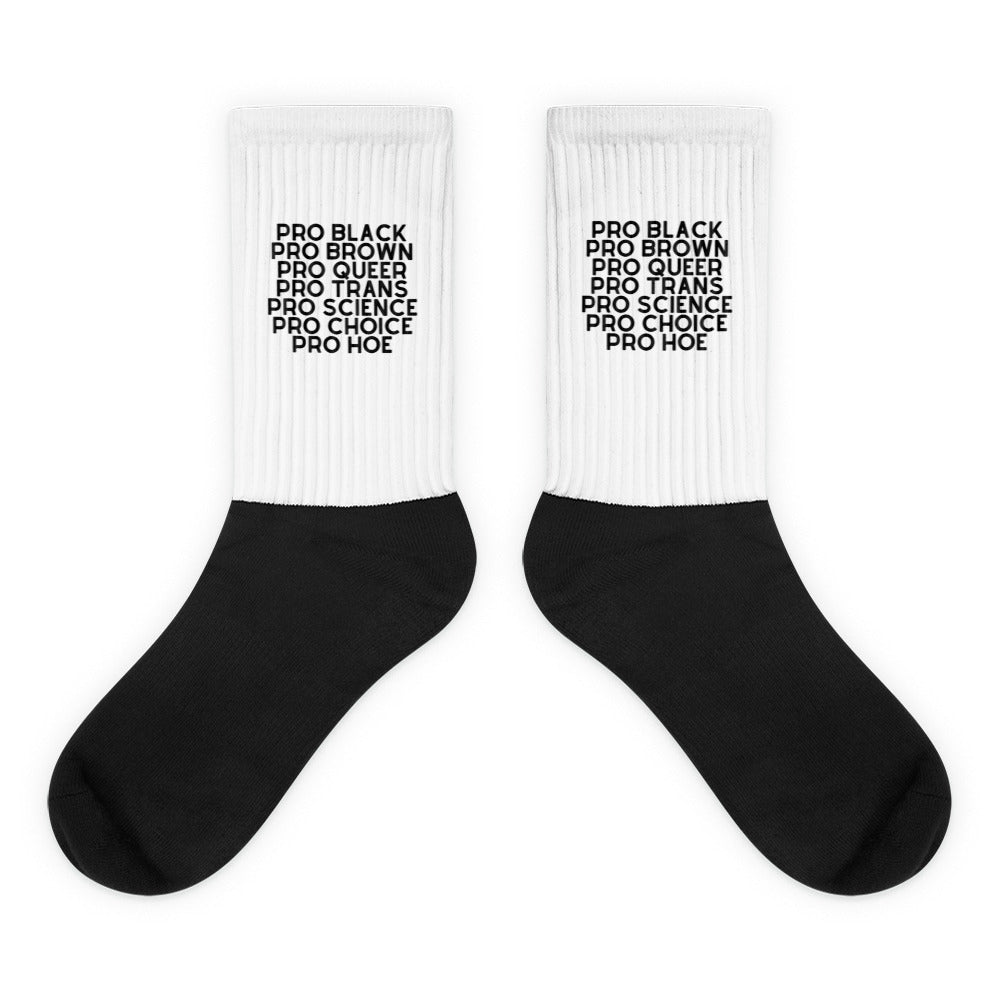 Pair of white-and-black crew socks reading “PRO BLACK PRO BROWN PRO QUEER PRO TRANS PRO SCIENCE PRO CHOICE PRO HOE”