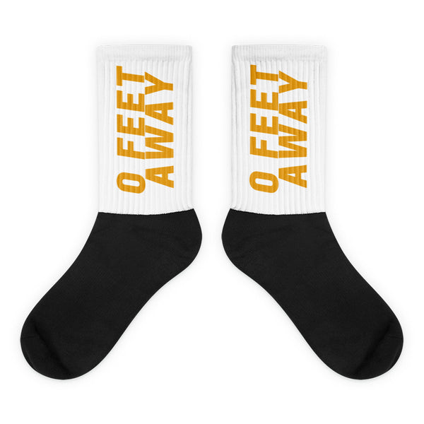 Zero Feet Away Grindr Socks feature a bold black foot and white leg with mustard-yellow 0 FEET AWAY text, embodying vibrant queer pride and self-expression with a comfortable, stylish flair.
