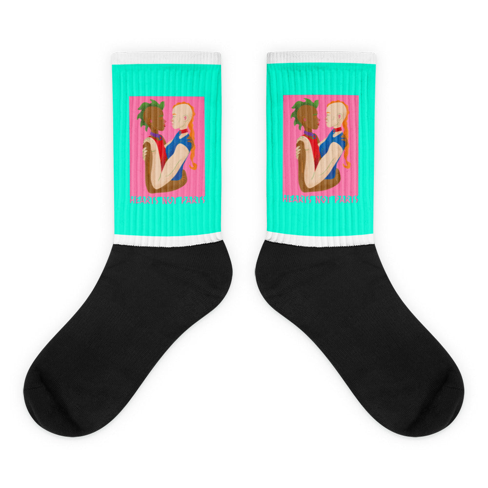 Pair of black and turquoise socks showing two embracing figures and “HEARTS NOT PARTS” text