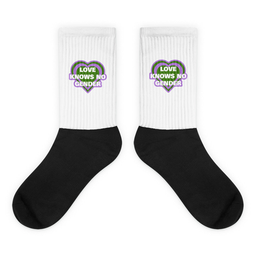 Pair of black-and-white socks with heart graphics reading “LOVE KNOWS NO GENDER”