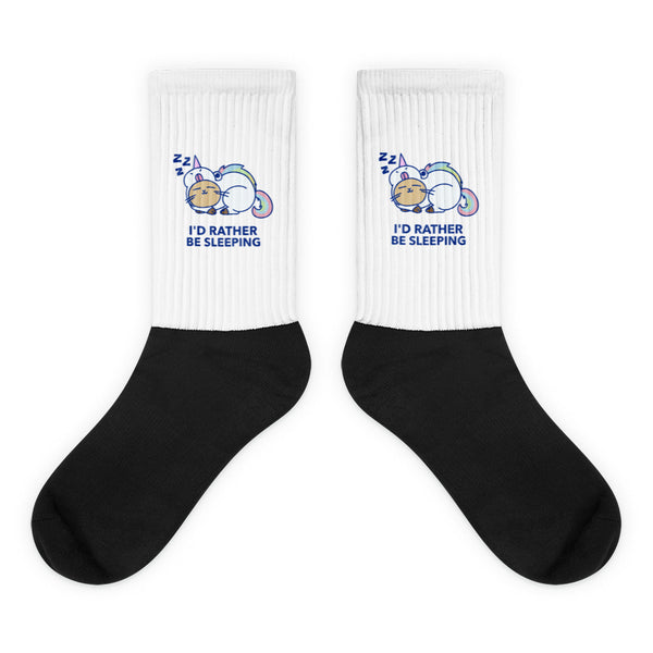 I'd Rather Be Sleeping Socks showcase a snoozing unicorn cartoon on white crew-length legs with a bold black foot, crafted from a 60% nylon blend, embodying bold, joyful queer self-expression and comfort.