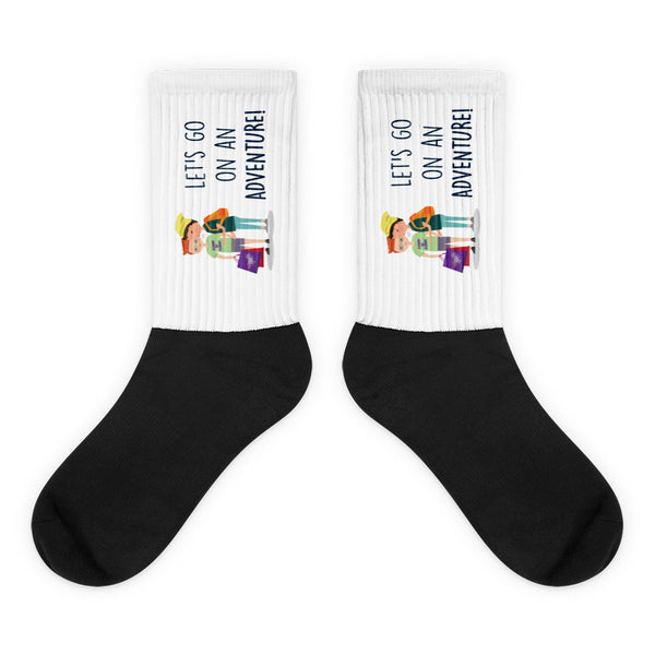 Let's Go On An Adventure Socks feature a bold black foot and ribbed white cuff adorned with cartoon hikers and empowering text, blending comfort and queer pride in a vibrant, expressive design.