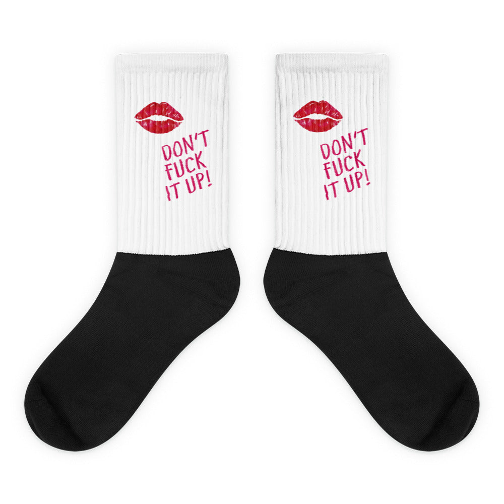 Pair of crew socks with white ribbed cuffs, red lips and “DON’T FUCK IT UP!” text, and black feet
