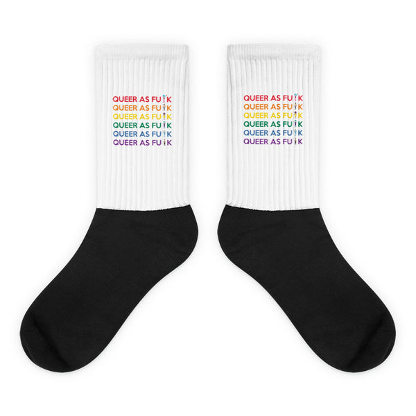 Queer As Fu*k Socks: Vibrant crew-length socks with a black foot and white ribbed top featuring QUEER AS FU¡K in rainbow colors, embodying prideful, expressive style with a cushioned, comfortable fit.
