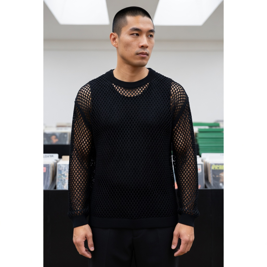 Black Mesh See-Through Long Sleeve Shirt in Black, styled on an adult model at an indoor record fair with black lacquer plinths, white skylights and a green stack of sleeves.