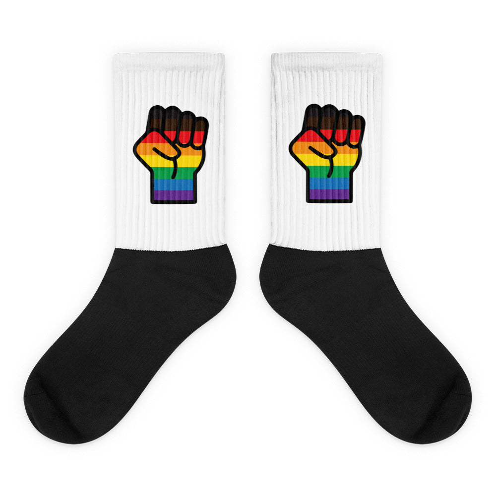 Pair of white crew socks with black feet and rainbow raised-fist graphics