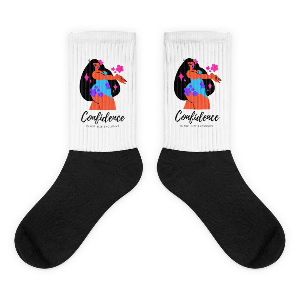 Pair of black socks with white ribbed cuffs showing a colorful woman and “Confidence” text