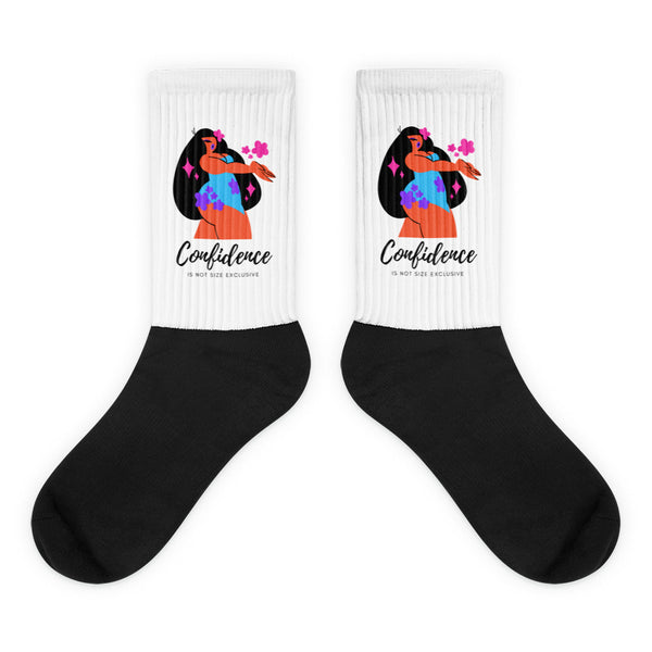 Pair of black socks with white ribbed cuffs showing a colorful woman and “Confidence” text