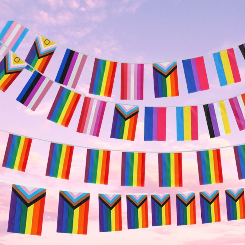 Rows of colorful LGBTQ+ flag pennants strung against a pink and purple sky