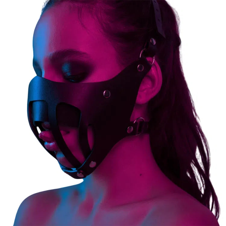Side-profile model wearing a black leather bondage mouth-cover mask with rivets
