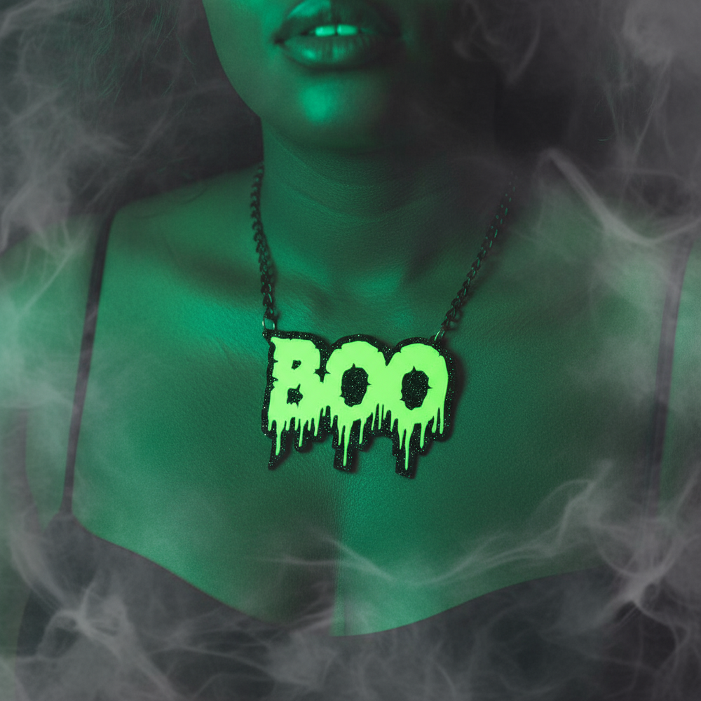 Close-up of a black chain necklace with a neon green dripping “BOO” pendant