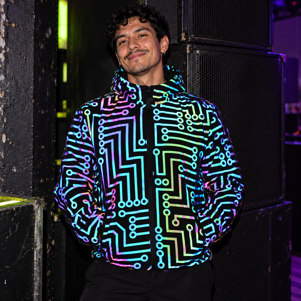 Fluorescent Circuit Reflective Festival Hoodie Jacket + Pants in Jacket Only, styled at a quiet black-walled corner beside a club speaker stack.