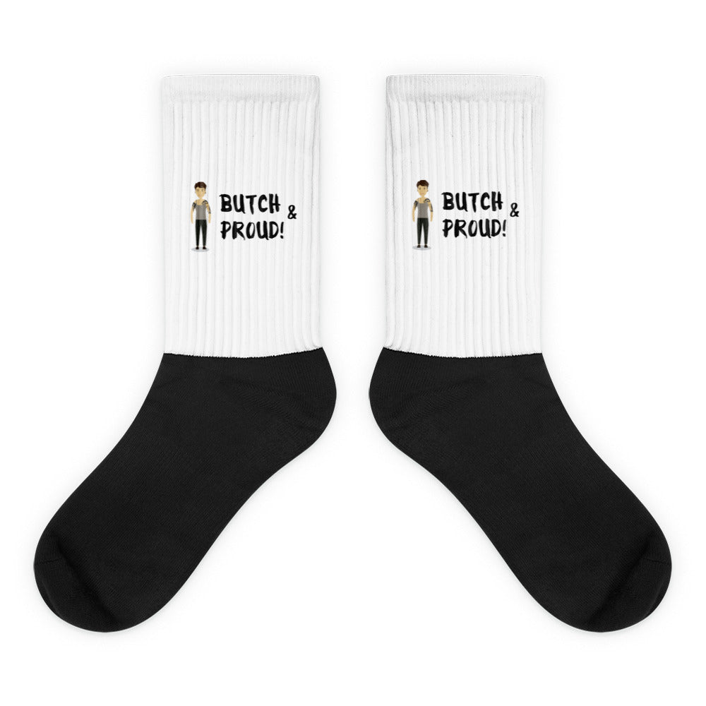 Pair of black-and-white ribbed socks reading “BUTCH & PROUD!” with cartoon figures