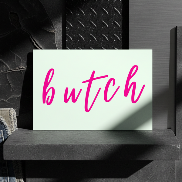 Butch Postcard with “butch” in bold pink cursive on white, set against dark stone, striped fabric