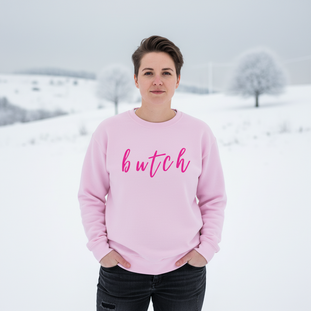 Front-facing model in a pink sweatshirt reading “butch” against a snowy landscape