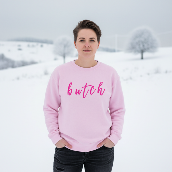 Front-facing model in a pink sweatshirt reading “butch” against a snowy landscape